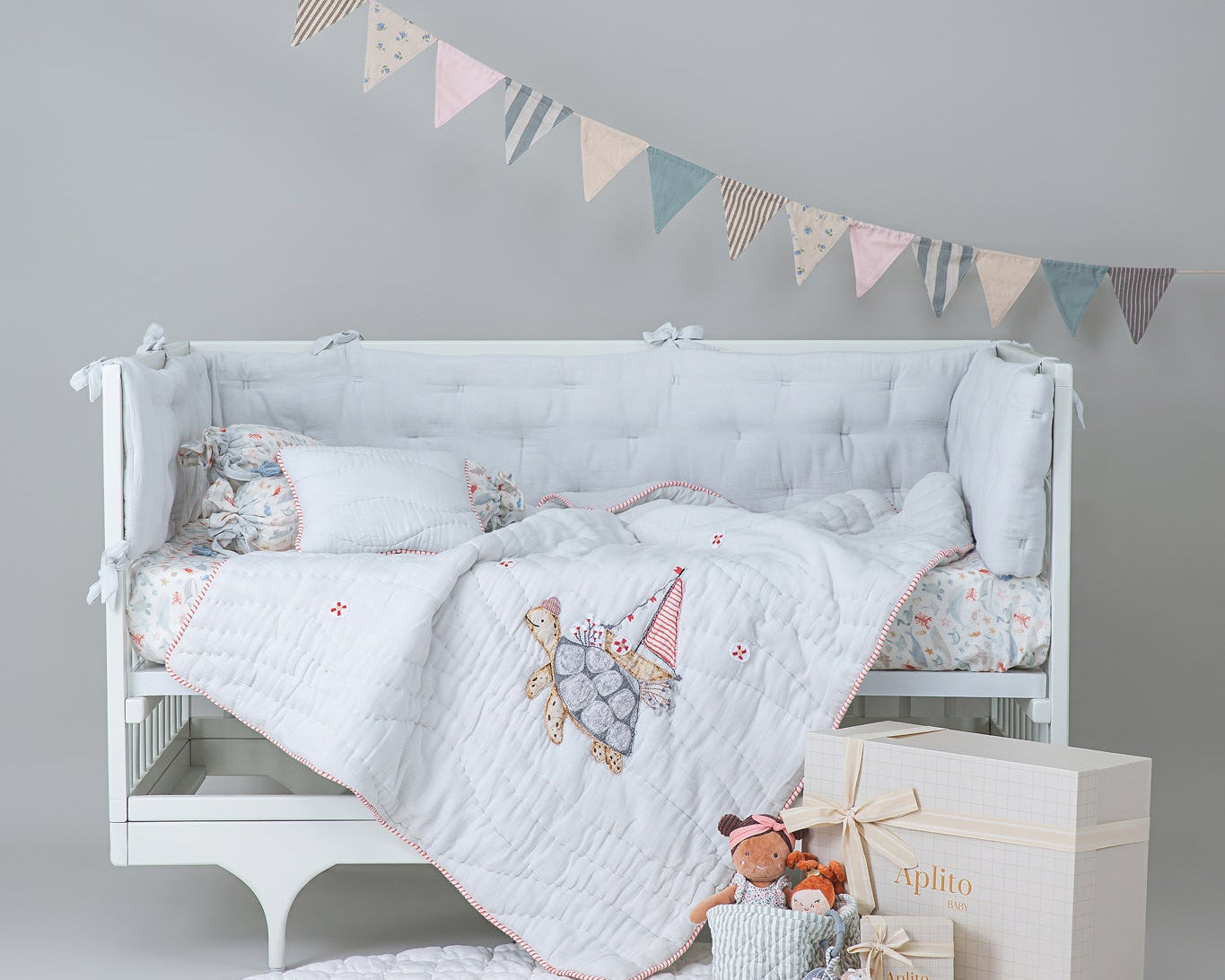 Aplito Turtle Tales bedding with a turtle-motif quilt and matching pillows displayed on a white cot.
